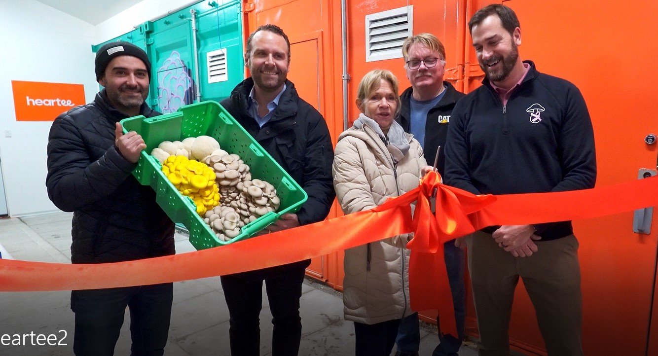 Ribbon cutting with the Mayor of Scugog and executives from Windmill Farms and Heartee holding a crate of fresh mushrooms.