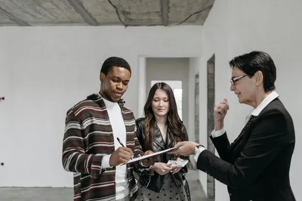 agent man signs document couple property real estate
